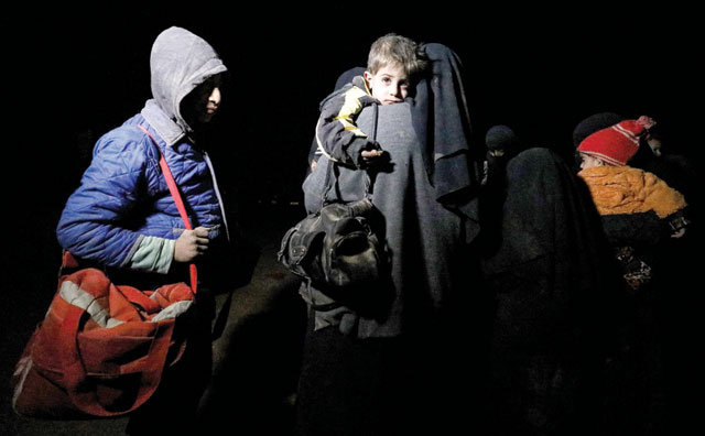 A woman carries a child as she walks with other children near the Omar oilfield in Deir Ezzor, Syria, on Friday, as she arrives with other fleeing families from pockets held by Daesh (AFP photo)