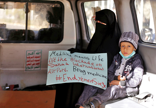 A woman holds a placard as she sits with her sick son in an ambulance waiting for the arrival of United Nations envoy to Yemen, Martin Griffiths, at Sanaa airport, Yemen, on Saturday (Reuters photo)