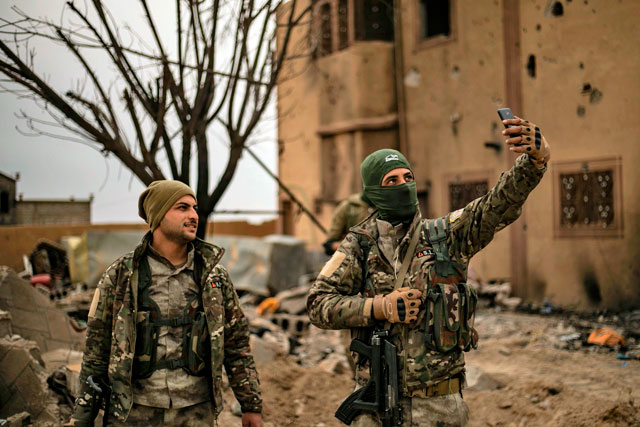 Members of the Syrian Democratic Forces (SDF) use a cellphone to take a ‘selfie’ photograph in the village of Baghouz in Syria's eastern Deir Ezzor province near the Iraqi border on Sunday, a day after the Daesh group's ‘caliphate’ was declared defeated by the US-backed Kurdish-led SDF (AFP photo)