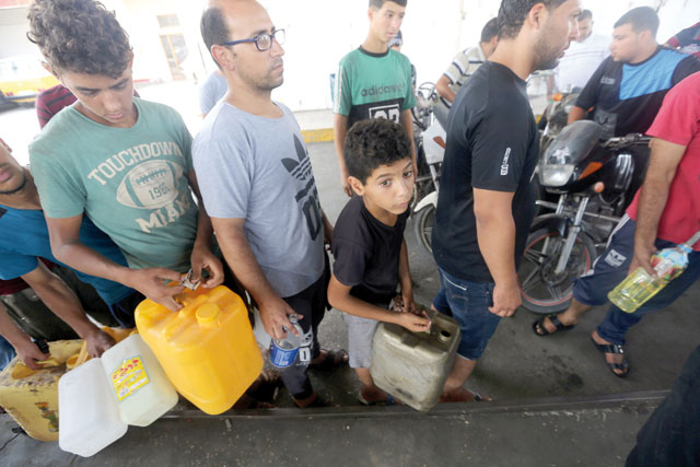 Palestinians wait to fill containers with fuel after Israel stopped the transfer of fuel and cooking gas into Gaza, at a petrol station in Khan Younis, in the southern Gaza Strip, on Tuesday (Reuters photo)