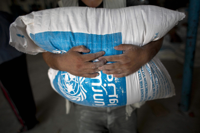A Palestinian man carries a bag of wheat flour distributed at an aid distribution centre of the United Nations Relief and Works Agency (UNRWA) in Rafah in the southern Gaza Strip on August 3, 2015 (AFP photo)
