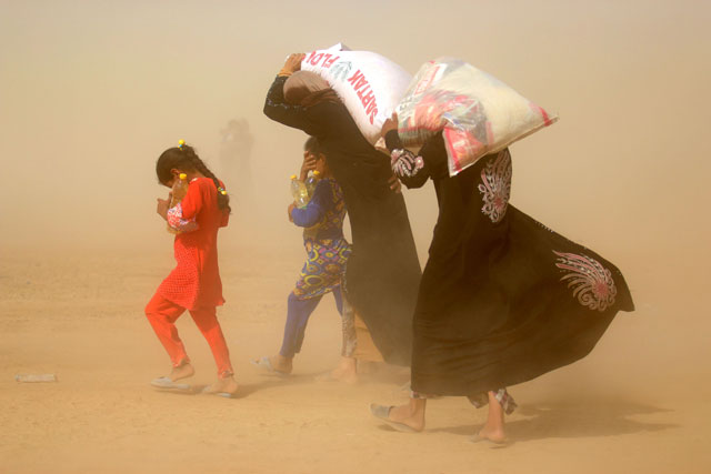 Displaced Iraqis who fled the government's operation against Daesh in Fallujah carry basic food items donated by an NGO on Monday  (AFP photo by Haidar Mohammed Ali)