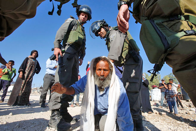 Palestinian Suleiman Hadhalin (centre) is surrounded by Israeli troops as he tried to prevent Israeli occupation authorities from destroying his house that they said was built without permission, on Tuesday, in the village of Um Al Kheir, south of the West Bank city of Hebron  (AFP  photo by Hazem Bader)