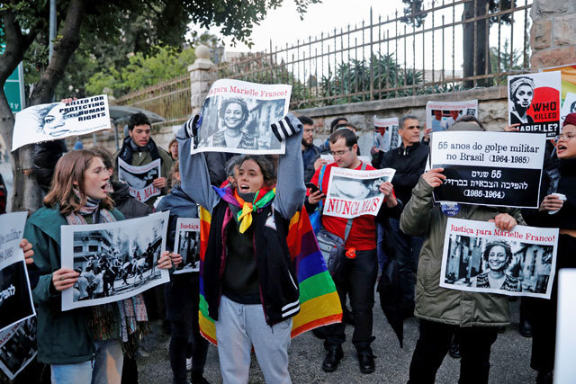 People hold placards as they protest against the visit of Brazilian President Jair Bolsonaro to Israel, during his meeting with Israeli Prime Minister Benjamin Netanyahu in Jerusalem, on Sunday (Reuters photo)