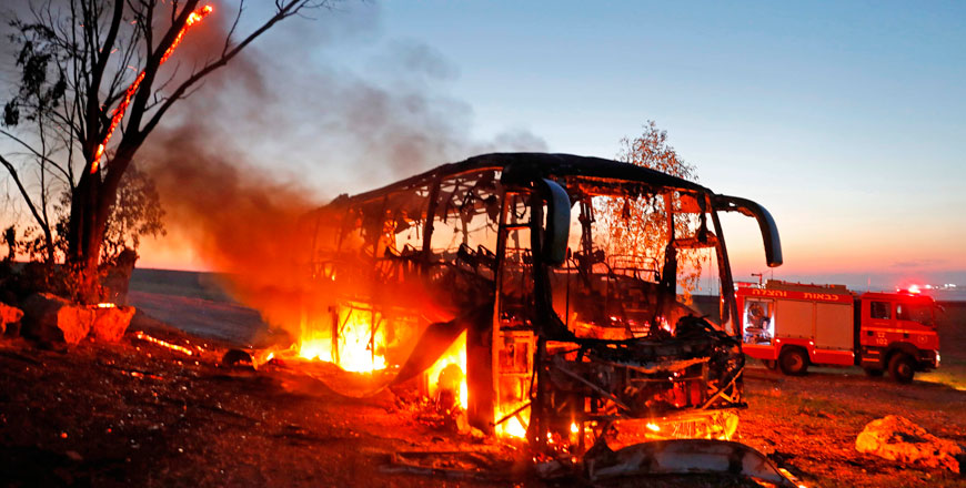 A bus set ablaze after it was hit by a rocket fired from the Gaza Strip, at the Israel-Gaza border near the kibbutz of Kfar Aza, on Monday (AFP photo)