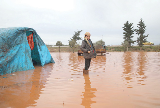 A Syrian boy stands in a water logged field outside a tent in the Cordoba camp for internally displaced persons, close to Batabu town, along the highway leading to the Syrian Bab Al Hawa border crossing with Turkey, in the northern Syrian Idlib province, on Wednesday (AFP photo)