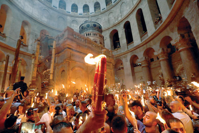 Christian Orthodox worshippers hold up candles lit from the Holy Fire as they gather in the Church of the Holy Sepulchre in Jerusalem’s Old City on Saturday during the Orthodox Easter (AFP photo)