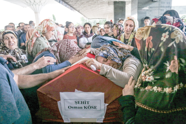 Relatives of Osman Kose, a 38-year-old Turkish diplomat killed in Iraq, mourn in front of the coffin covered with the Turkish national flag, during the funeral ceremony in Ankara, on Thursday  (AFP photo)