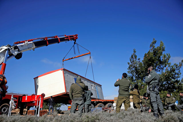 A pre-fabricated home is lowered onto a tow truck as it is removed during an evacuation by Israeli forces of Jewish settlers from Amona, an illegal outpost in the Israeli-occupied West Bank, on Thursday (Reuters photo)