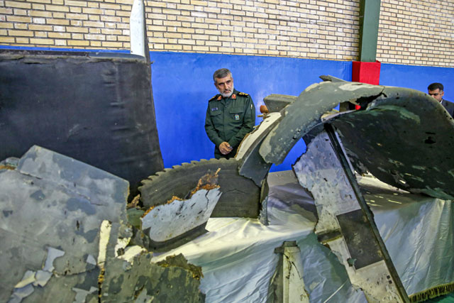   General Amir Ali Hajizadeh (centre), Iran's head of the Revolutionary Guard's aerospace division, looks at debris from a downed US drone reportedly recovered within Iran's territorial waters and put on display by the Revolutionary Guard in the capital Tehran on Friday (AFP photo)