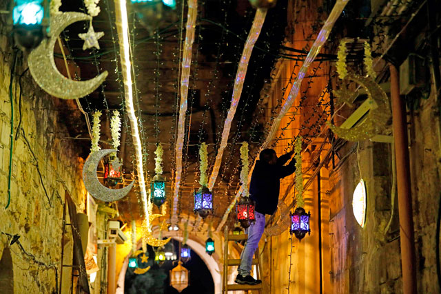 Palestinian man hangs traditional lanterns at the entrance of Al Aqsa Mosque in Jerusalem's old city on May 4 (AFP photo)