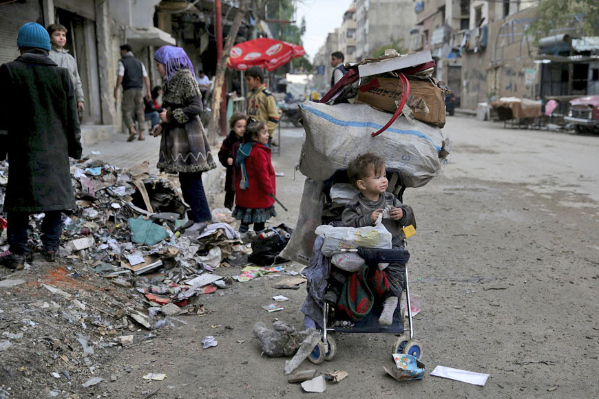 A child rests inside a stroller filled with cartons collected to use for heating in the town of Douma, eastern Ghouta in Damascus, Syria, on Wednesday (Reuters photo)