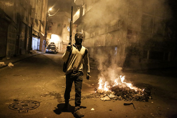 An armed Kurdish militant walks in the Okmeydani district of Istanbul during a demonstration against recent curfews imposed on Kurdish towns on Tuesday (AFP photo)