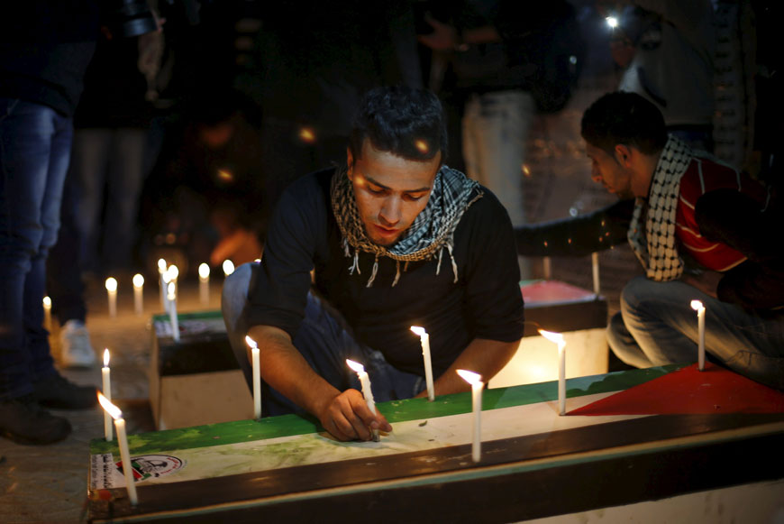 A Palestinian places a candle on a symbolic coffin during a rally to pay tribute to Palestinians who organisers said were killed recently by Israeli troops, on Christmas day, on Friday, in Gaza City (Reuters photo)