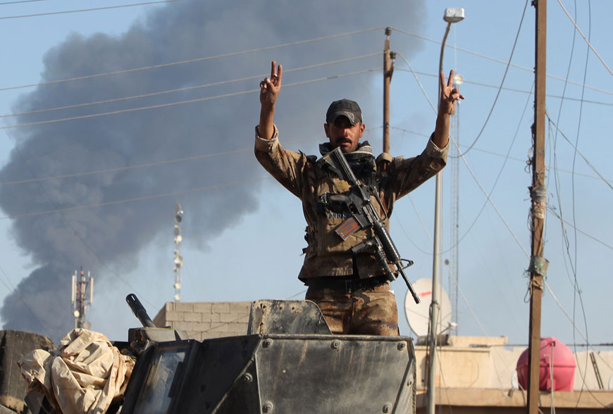 A member of Iraq’s elite counterterrorism service flashes the ‘V’ for victory sign as smoke from a controlled explosion billows in the background on Tuesday on the outskirts of Ramadi, the capital of Iraq’s Anbar province, about 110 kilometres west of Baghdad, after Iraqi forces recaptured it from the Daesh terror group (AFP photo)