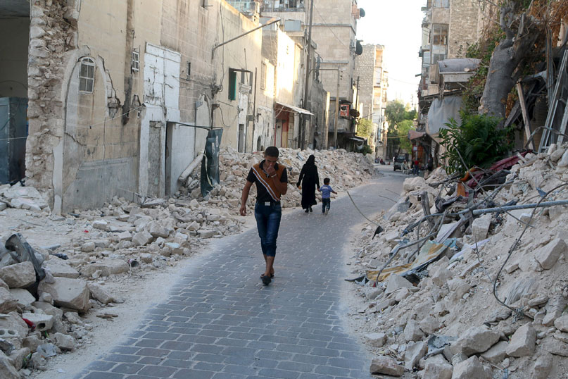 Residents walk past damaged buildings in a rebel-controlled area of Aleppo on Friday (Reuters photo)