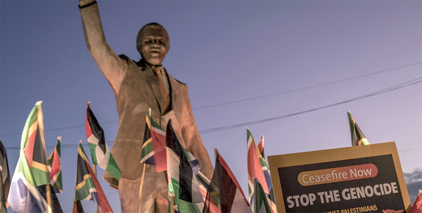 People raise flags and placards as they gather around a statue of late South African president Nelson Mandela to celebrate a landmark ‘genocide’ case filed by South Africa against Israel at the International Court of Justice, in the occupied West Bank city of Ramallah on Wednesday (AFP photo)