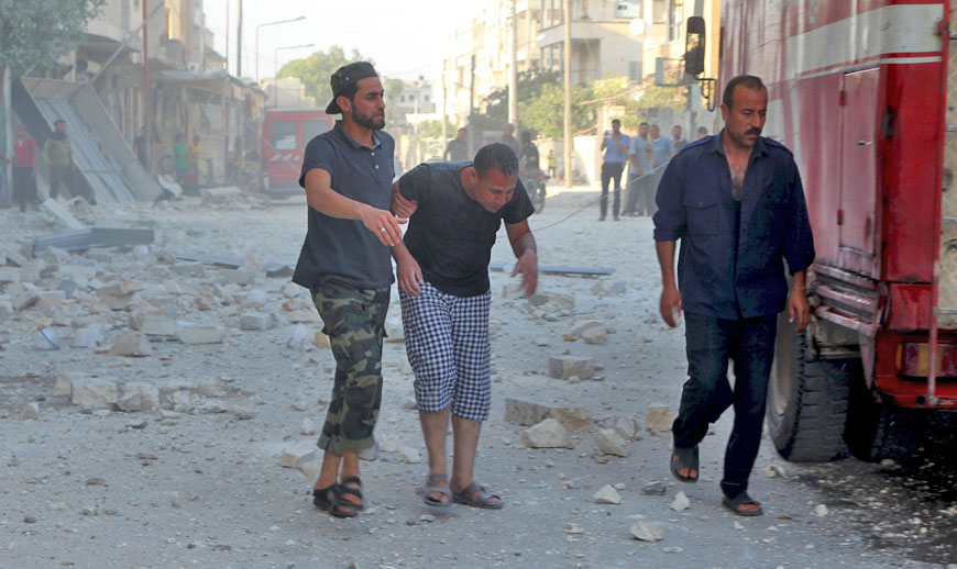 A man covered in dust is helped at a site hit by what activists said was an air strike by forces loyal to Syria’s President Bashar Assad, at Al Thawra neighbourhood in Idlib city, on Monday (Reuters photo)