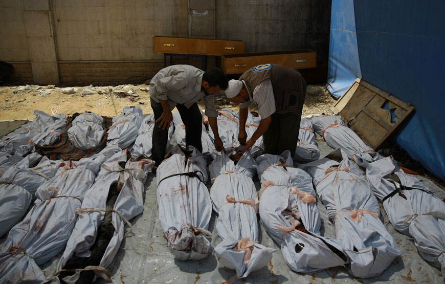 A Syrian emergency personnel and a civilian inspect the bodies of Syrian men wrapped in plastic bags outside a make-shift hospital in the rebel-held area of Douma, east of the capital Damascus, following reported air strikes by regime forces, on Wednesday (AFP photo)