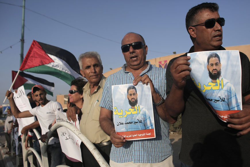 Arab Israeli protesters wave Palestinian flags and hold posters of Mohammed Allan, a Palestinian prisoner who is on a  long-term hunger strike, during a rally calling for his release in the southern Israeli bedouin city of Rahat on Tuesday (AFP photo)