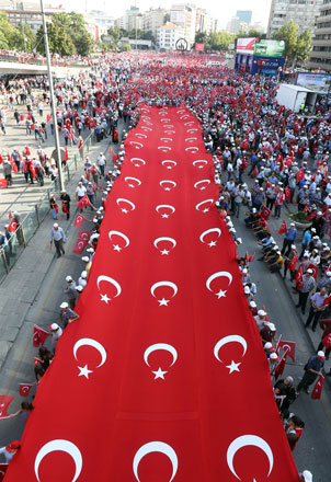 People walk with a giant banner with the Turkish national emblem as they demonstrate to condemn terrorism and attacks against Turkish security forces in Ankara, on Thursday (AFP photo)