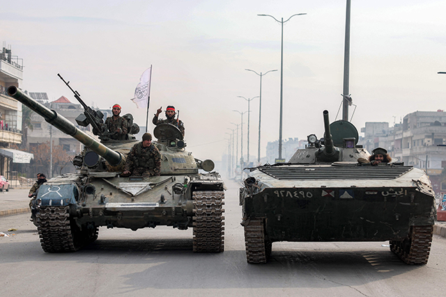 Fighters loyal to the interim Syrian government ride atop a main battle tank and in an infantry fighting vehicle (IFV) during a patrol in the Zahra district of Syria's west-central city of Homs on January 4, 2025 (AFP photo)