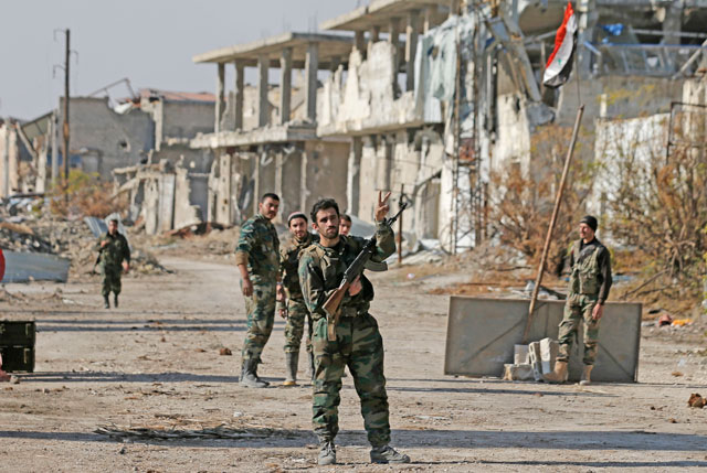 A Syrian army soldier flashes the victory sign as he comes back from the frontline with his commanders in Karam Al Tarab, east of Aleppo, on Sunday (AP photo)