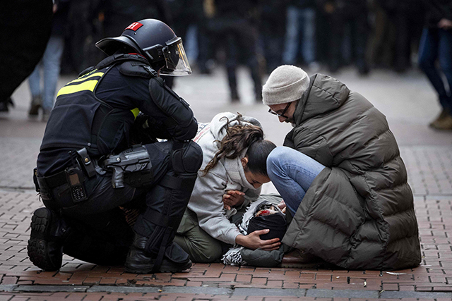 A police officer stands next to demonstrators helping a bloodied pro-Palestinian protester near Dam Square during a Pro-Palestinian protest in Amsterdam on November 10, 2024 (AFP photo)