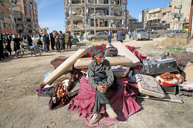 An earthquake survivor waits with his belongings at the outside of the damaged buildings in Sarpol-e Zahab town of Kermanshah, Iran, on Monday following a 7.3 magnitude earthquake that hit Iraq and Iran (Anadolu Agency photo)