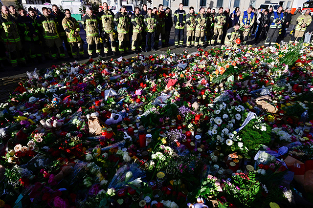 Members of Magdeburg's fire department stand at a makeshift memorial outside the Johanniskirche (Johannes Church), near the site of a car-ramming attack on a Christmas market in Magdeburg, eastern Germany, on December 22, 2024 (AFP photo)