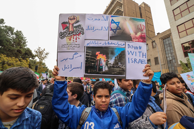 A boy holds a placard with anti-US slogans during a rally outside the former US embassy in Tehran as Iranians mark the 45th anniversary of the start of the Iran hostage crisis, on November 3, 2024 (AFP photo)