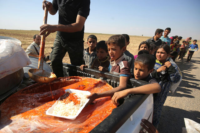 Iraqi children receive food from a charity in a village on the outskirts of Hawija on Friday, a day after Iraqi forces retook the northern city from the Daesh extremists (AFP photo)