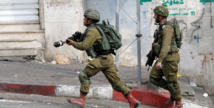 An Israeli soldier runs during confrontations with Palestinians in Hebron, in the occupied West Bank, on Monday (Reuters photo)