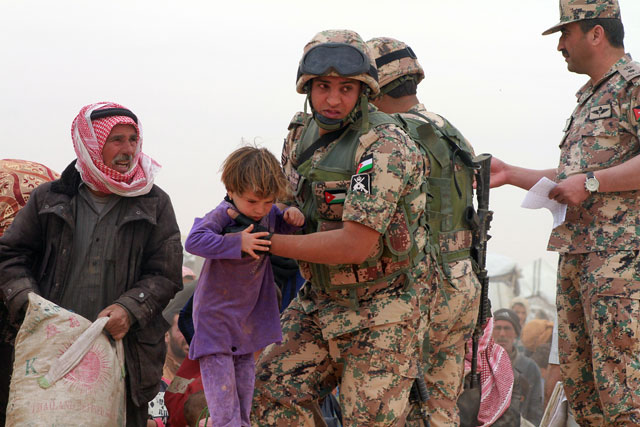Border Guards help a Syrian family cross the border into Jordan on Wednesday (Photo by Hassan Tamimi)