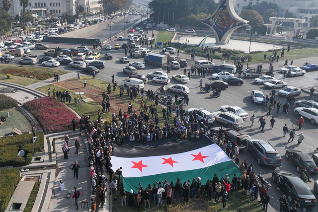 People celebrate holding a large Syrian opposition flag at Umayyad Square in Damascus on December 9, 2024 (AFP photo)