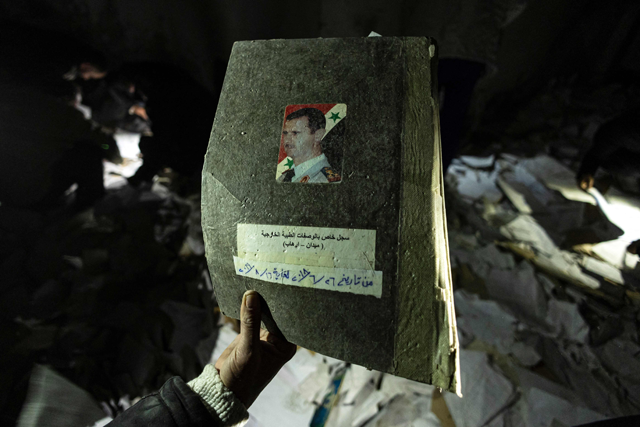 A man displays a register bearing the face of ousted president Bashar Al Assad at the Saydnaya prison in Damascus on December 11, 2024 (AFP photo)
