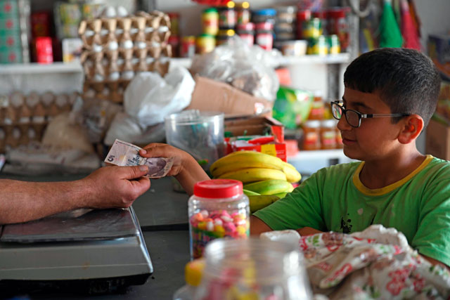 A boy pays a merchant with a Turkish lira banknote at a shop in the town of Jindayris, in the Afrin region of the northern Syrian rebel-held province of Aleppo, on Wednesday (AFP photo)