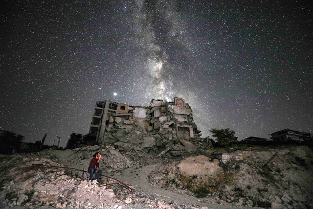 This long-exposure photo taken early on Saturday shows a man smoking past buildings destroyed by prior bombardment in the town of Ariha in Syria's rebel-held northwestern Idlib province, as the Milky Way galaxy is seen in the night sky above (AFP photo)