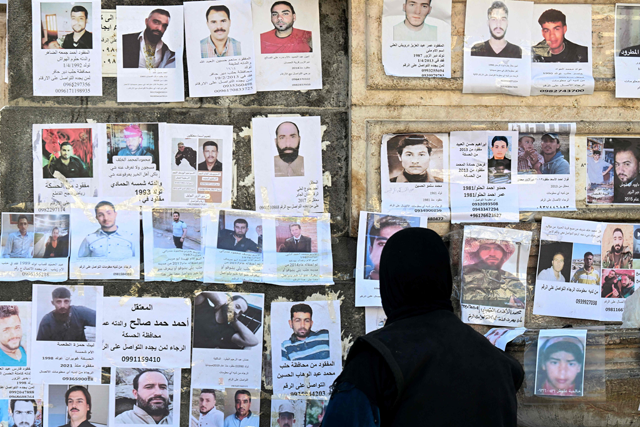 A Syrian woman looks at notes for missing people posted by relatives looking for loved ones, at Marjeh Square in Damascus, on December 18, 2024 (AFP photo)