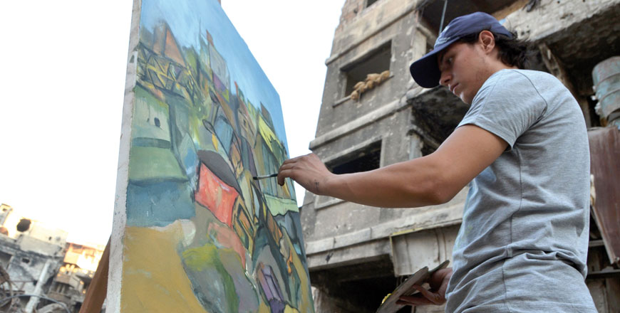 An artist paints war-damaged buildings in the Yarmouk Palestinian refugee camp on the southern outskirts of the capital Damascus on August 15 (AFP photo)