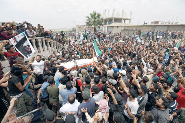   A photo taken on Sunday shows Syrians waving rebel flags and portraits of Abdel-Basset Al Sarout during the funeral of Syrian goalkeeper turned rebel fighter on June 8 of wounds sustained fighting regime forces in northwestern Syria (AFP photo)