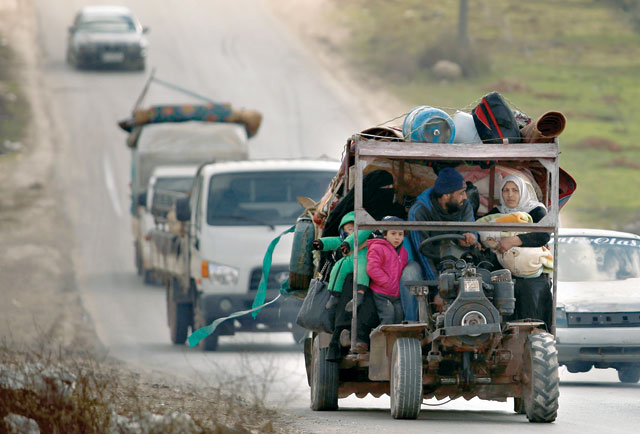 A Syrian family rides on a tractor turned into a make-shift truck through the town of Ariha in the northern countryside of Syria's Idlib province on Monday, as people flee from the south of Idlib amidst an ongoing government forces' offensive (AFP photo)