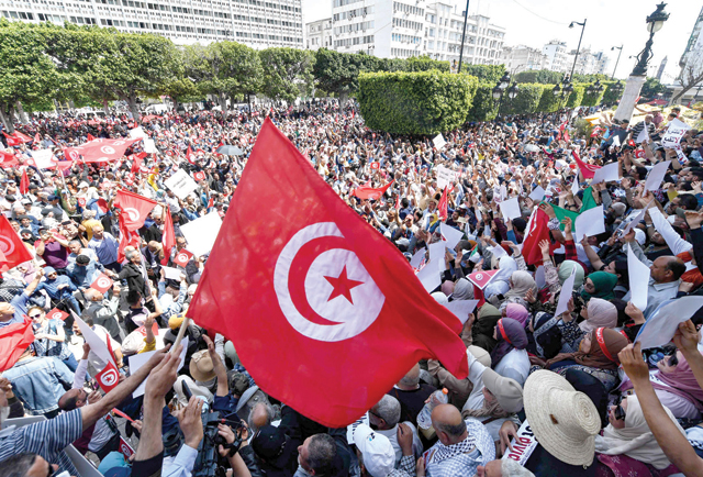 Tunisian protesters wave flags and raise placards as they demonstrate against their president in the capital Tunis, on Sunday (AFP photo)