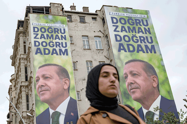 A woman walks past electoral posters bearing portraits of Turkish President and leader of the Justice and Development (AK) Party, Recep Tayyip Erdogan and a slogan reading in Turkish 'Right time, right man' in Istanbul on Friday, ahead of the May 14 presidential and parliamentary elections (AFP photo)