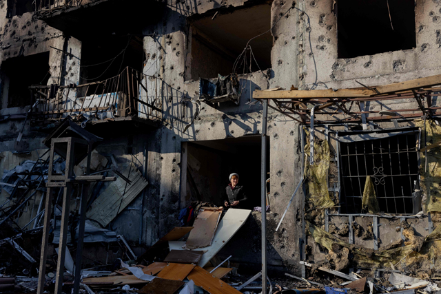 A woman stands by a windowless window in her destroyed residential building following a strike in Dobropillia, Donetsk region, on March 8, 2025, amid the Russian invasion of Ukraine (AFP photo)