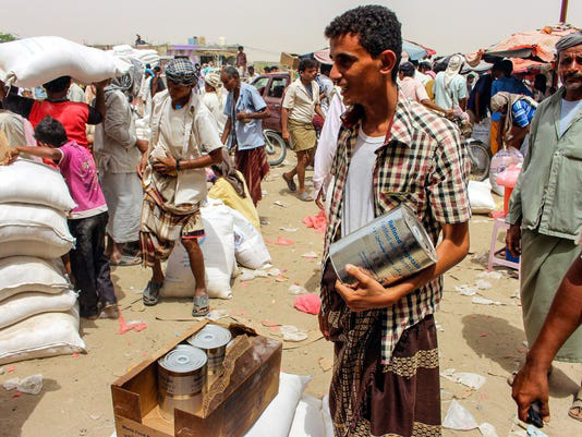 Yemeni civilians receive food aid for displaced people who fled battles in the Red Sea province of Hodeida (AFP photo)