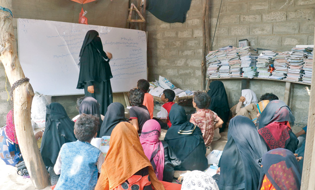 Yemeni teacher Amina Mahdi (left) gives a lesson to children sprawled across the floor of her home in the rural area of Muhib, in the southern province of Hodeida, on September 1 (AFP photo)