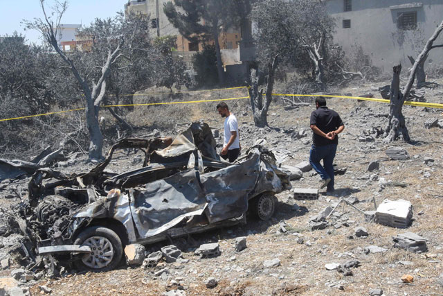   Men check a destroyed vehicle in the aftermath of an Israeli air strike near Lebanon's southern village of Jmaijmeh, on Friday (AFP photo)
