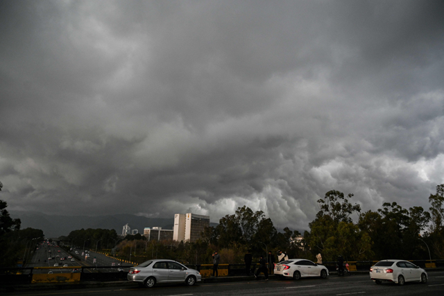 Commuters drive along a road as dark clouds are photo over the skies of Islamabad on Saturday (AFP photo)