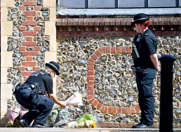 A police officer lays flowers, given by a member of the public, at an entrance of Forbury Gardens park in Reading, west of London, on Monday, the scene of the June 20 stabbing spree (AFP photo)
